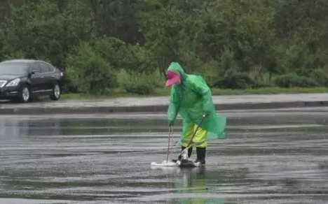 环卫工人将透明雨衣穿在反光工作服外面，挡住了反光材料