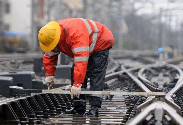 铁路工人穿着橘红色的反光衣，每天工作在铁道上，保护着铁路的顺畅运行